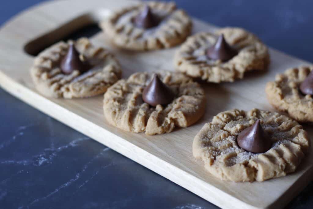 Overhead of peanut butter cookies on a cutting board with hershey kisses on top