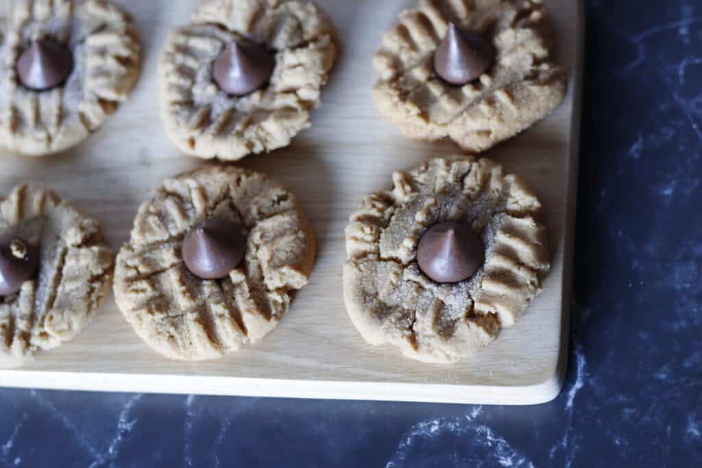 Overhead of peanut butter cookies on a  cutting board with hershey kisses on top 