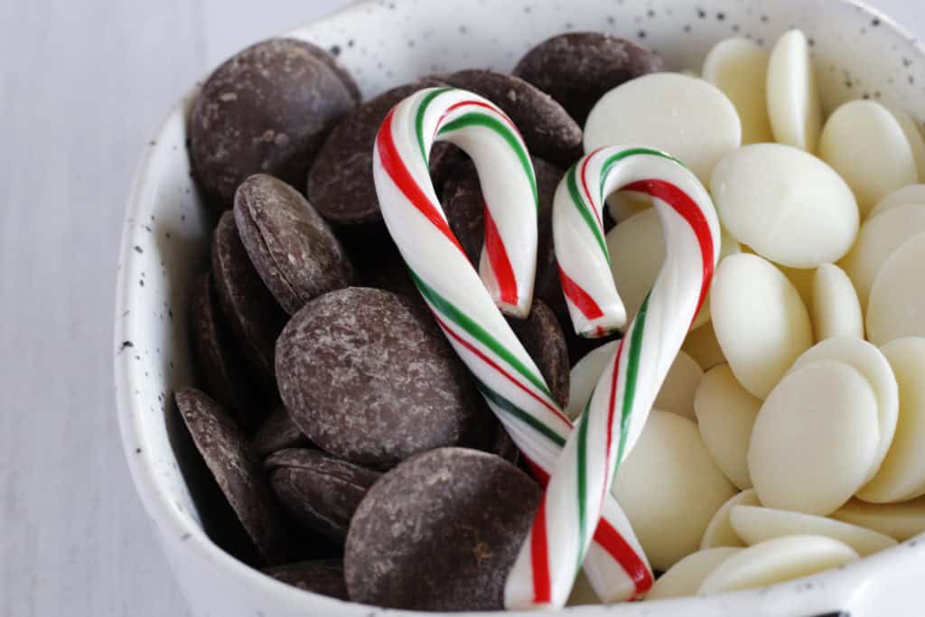 Bowl of chocolate and white chocolate melting candies with candy canes in the shape of a heart on top