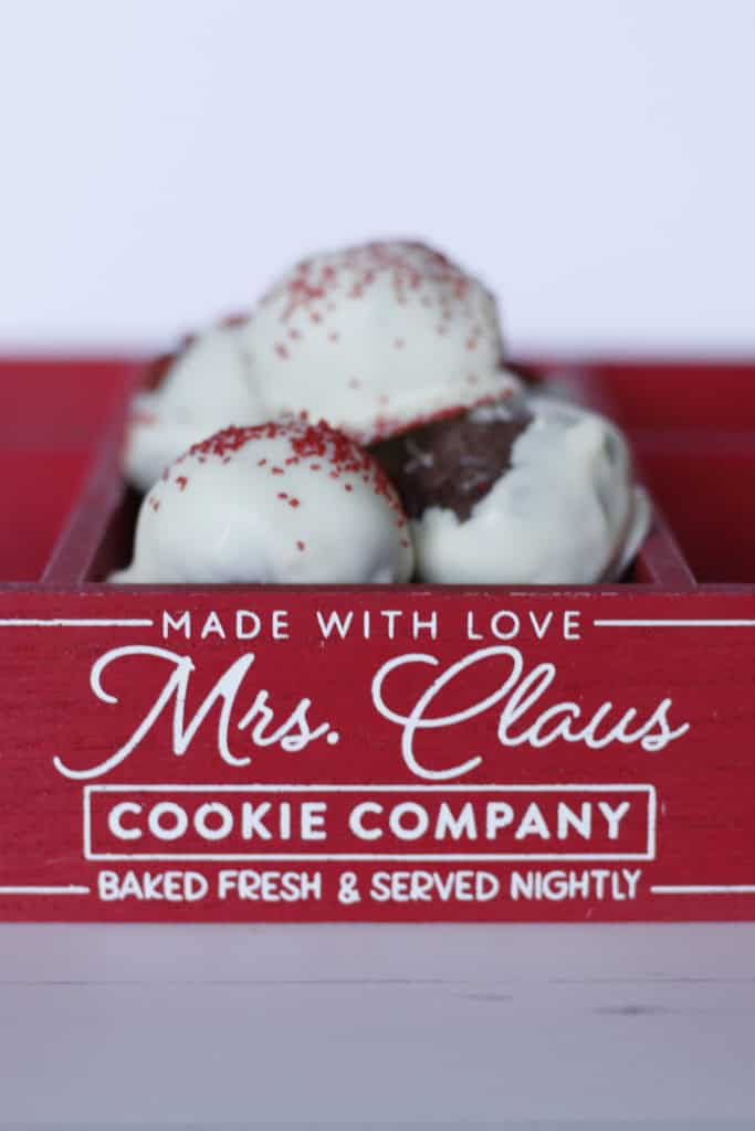 Frozen ice cream scoops with red sprinkles in a Mrs. Claus Cookie Company red box, showcasing festive dessert offerings.