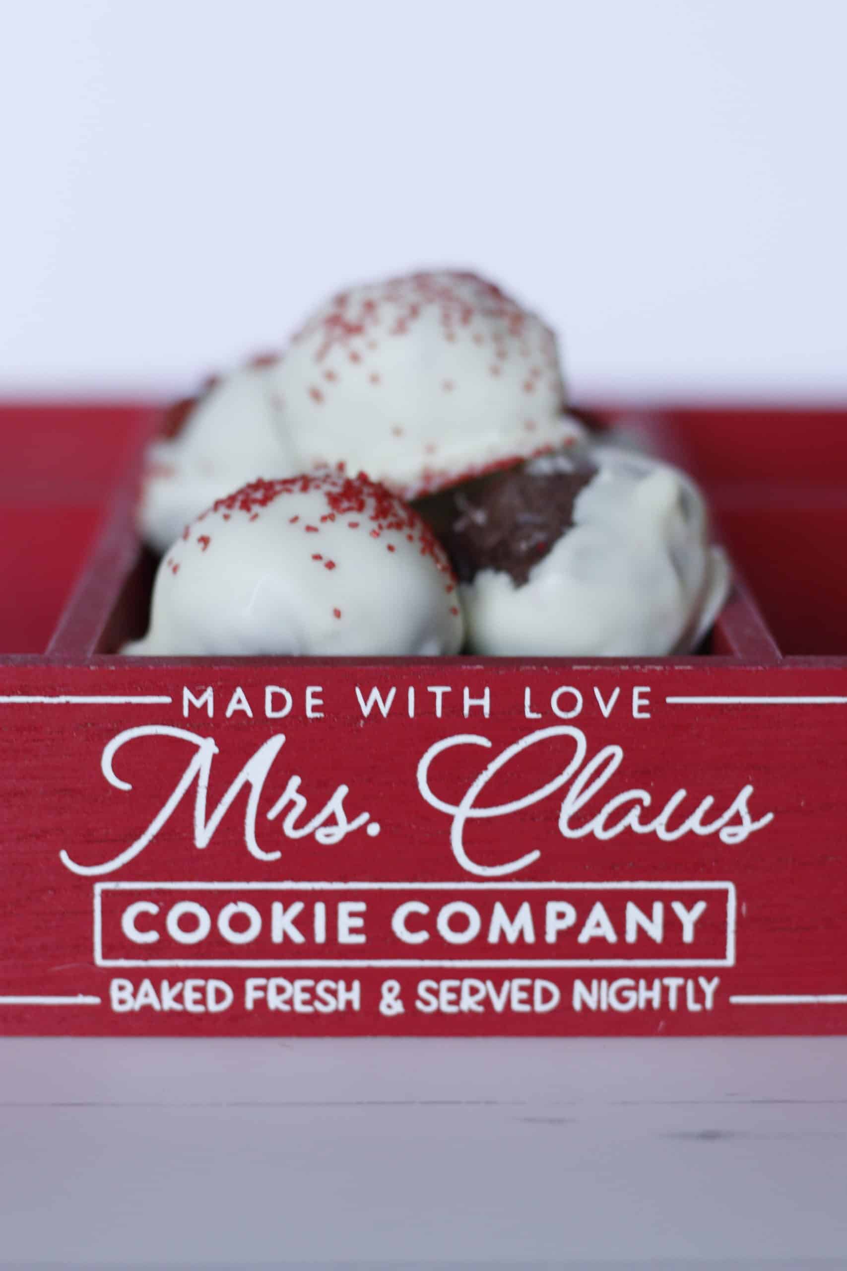 Frozen ice cream scoops with red sprinkles in a Mrs. Claus Cookie Company red box, showcasing festive dessert offerings.