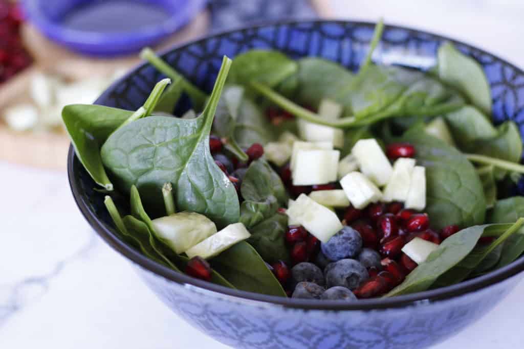 Spinach salad with blueberries and pomegranate in a blue bowl