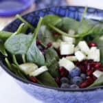 Spinach salad with blueberries and pomegranate in a blue bowl