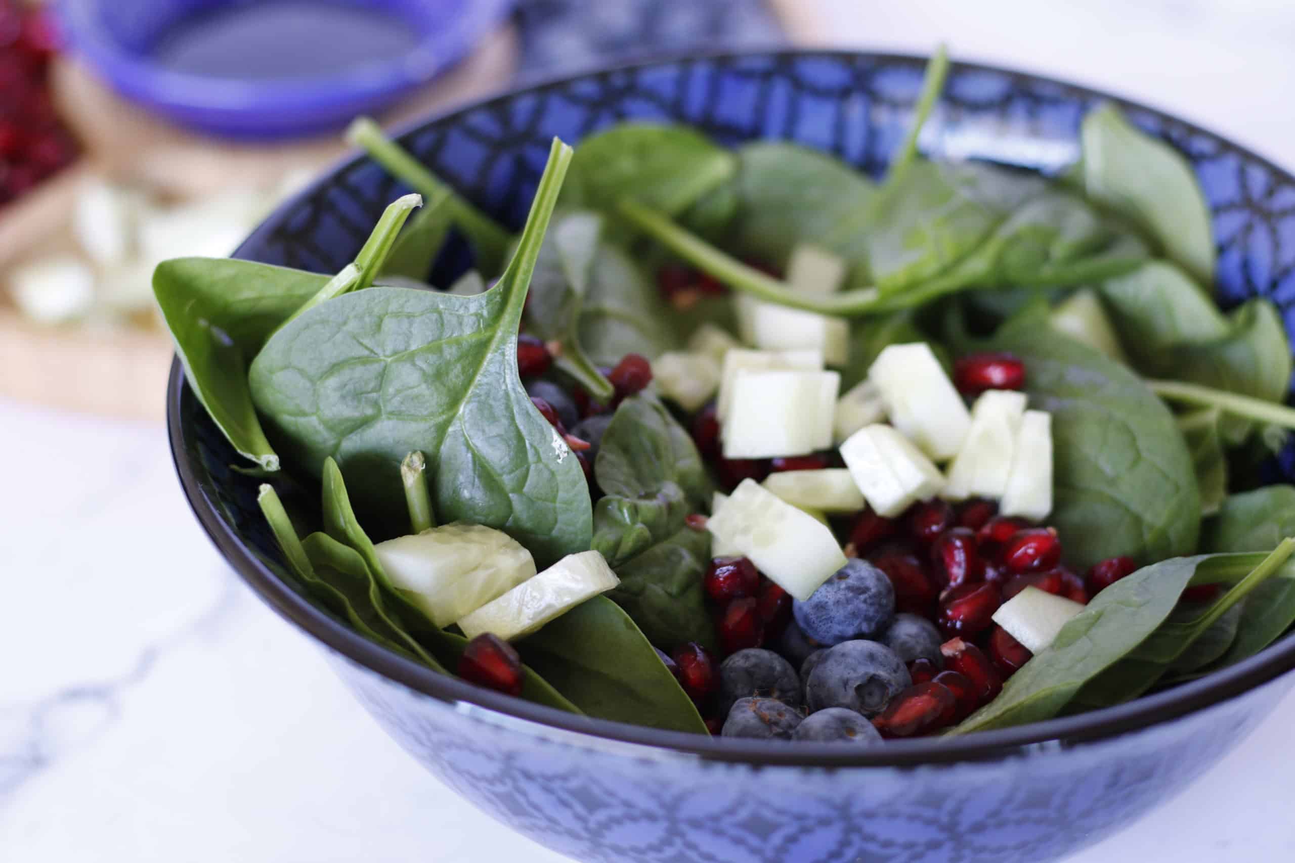 Spinach salad with blueberries and pomegranate in a blue bowl