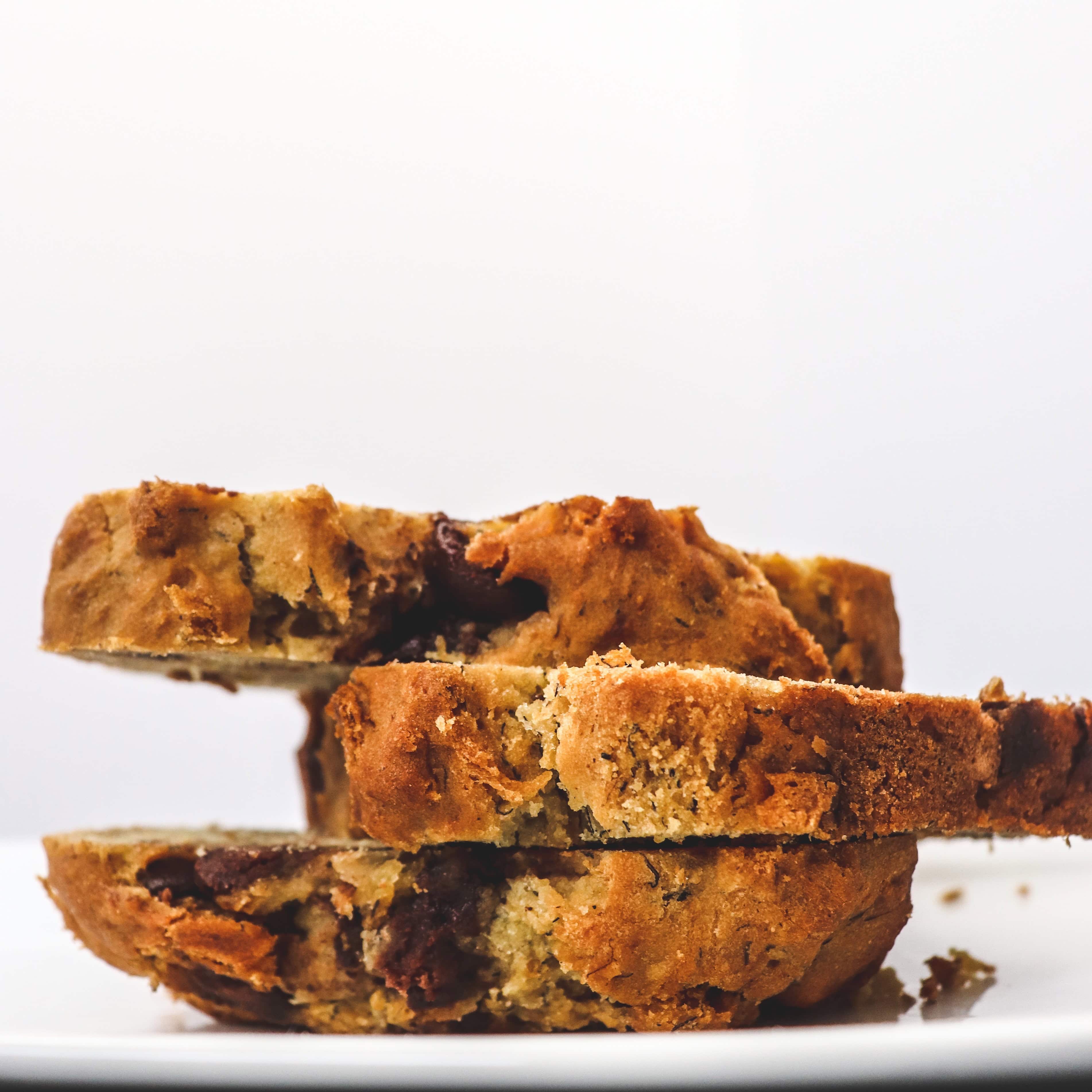 Chocolate chip cookies with gooey chocolate chunks, stacked on a white surface against a plain white background. Freshly baked, crispy edges, soft centers, perfect for snack or dessert.