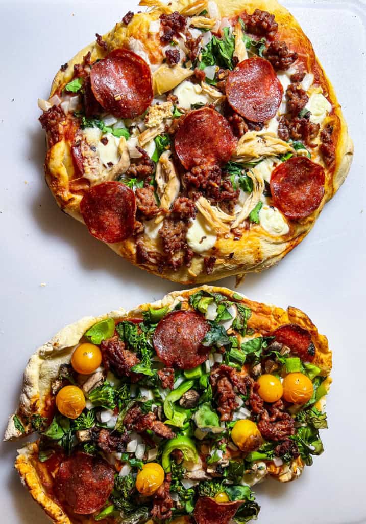 Savory pizza with pepperoni, sausage, greens, and cheese on a white background.