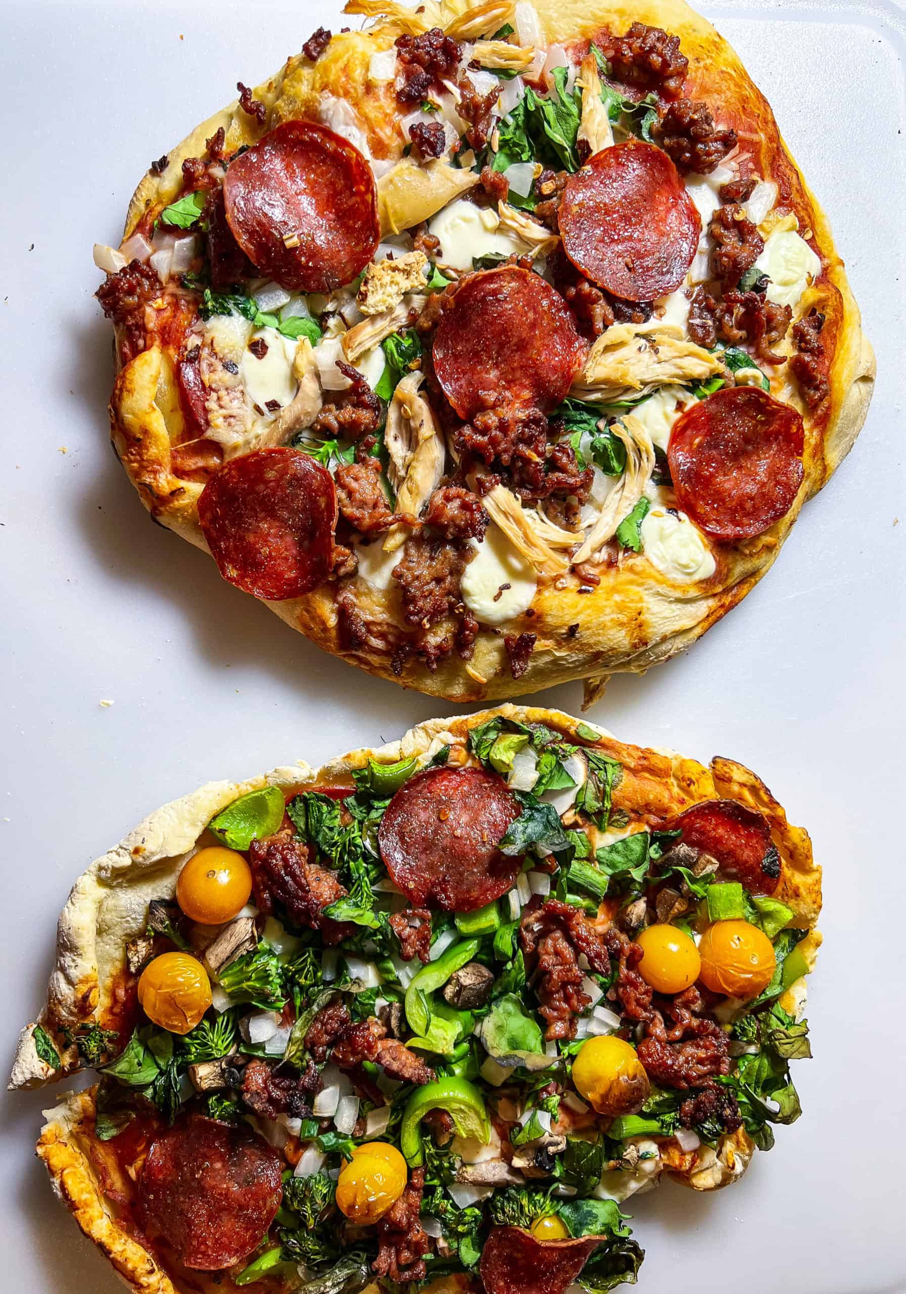 Savory pizza with pepperoni, sausage, greens, and cheese on a white background.