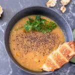 Apple and butternut squash soup with fresh pepper and parsley on top and a slice of toasted bread