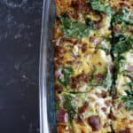 Overhead view of a breakfast quiche with eggs, sausage and spinach.