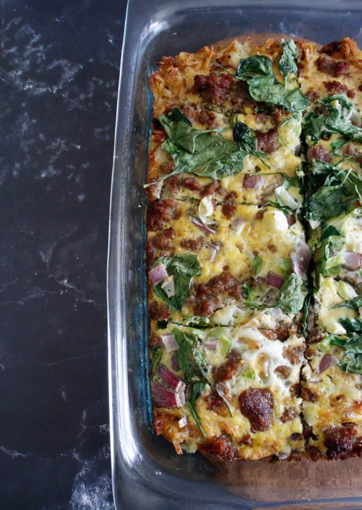 Overhead view of a breakfast quiche with eggs, sausage and spinach.