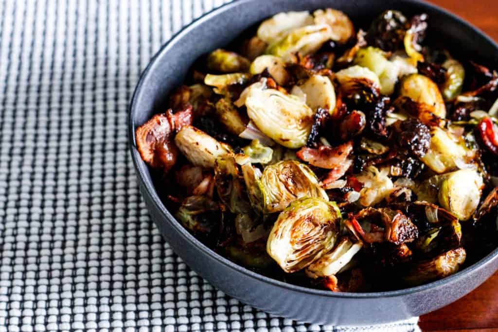 Roasted brussels sprouts and bacon in a serving bowl on a table