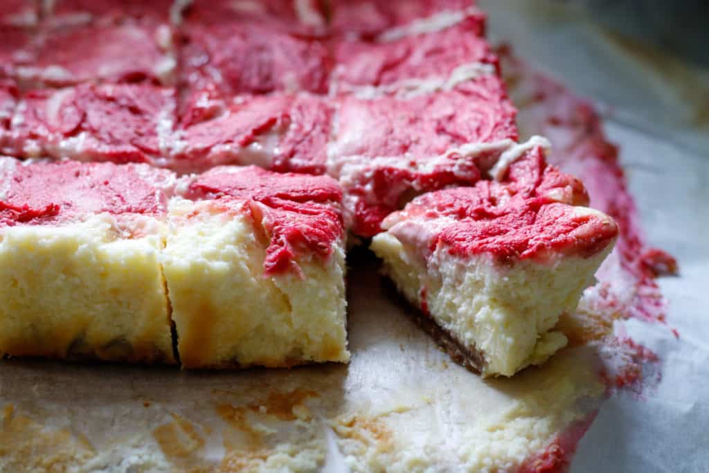 Raspberry cheesecake bars sliced on a round plate