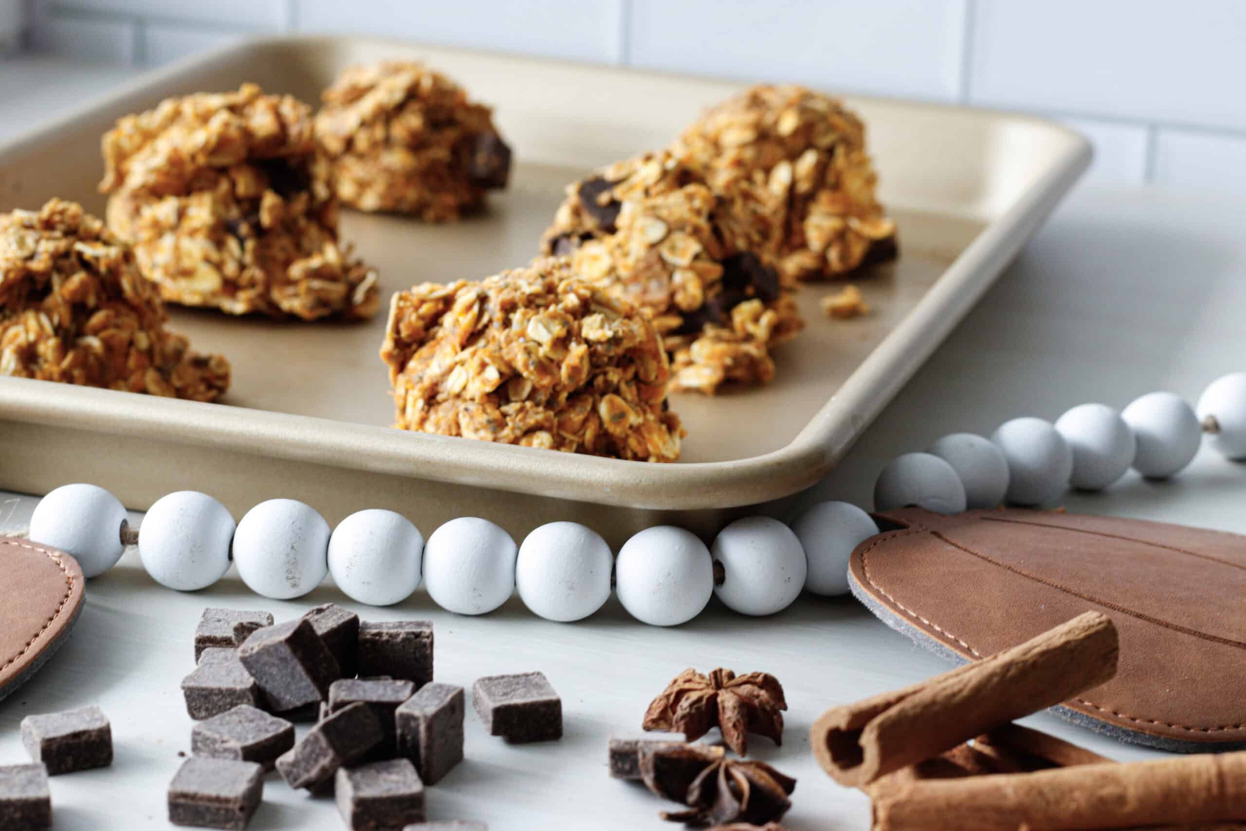 Pumpkin oat energy bites on a baking sheet with chocolate chips in the foreground