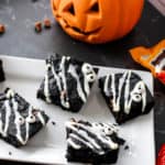 Spooky brownies with candy eye balls surrounded by jack-o-lanters and candy bars.