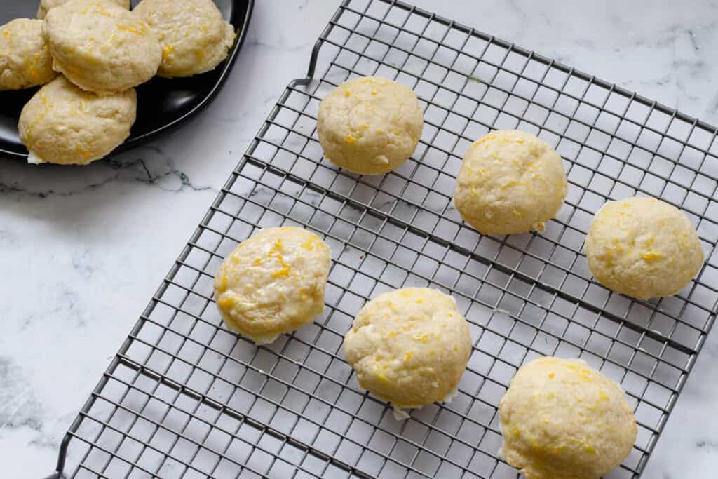 Light orange cookies with a shiny glaze laid out on a cooling rack