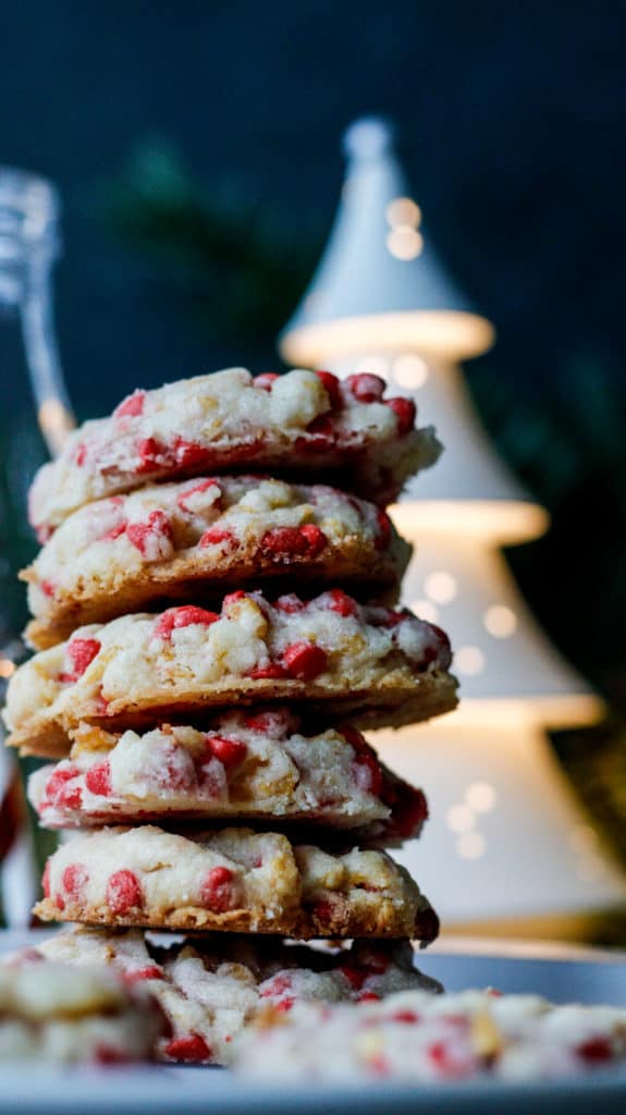 A stack of cookies with cherry chips with a whimsical white christmas tree in the background.