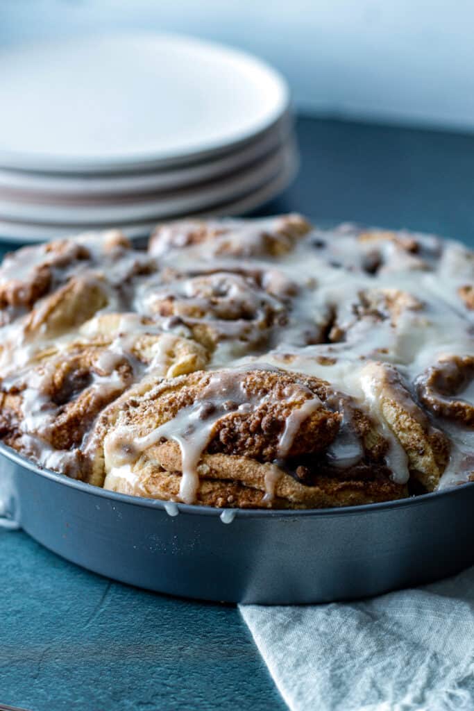 Circular pan of cinnamon rolls side view on black table with white napkin