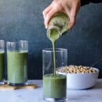 A vibrant green smoothie being poured into a clear glass, showcasing a nutritious blend of leafy greens, fruits, and wholesome ingredients for a refreshing and energizing beverage