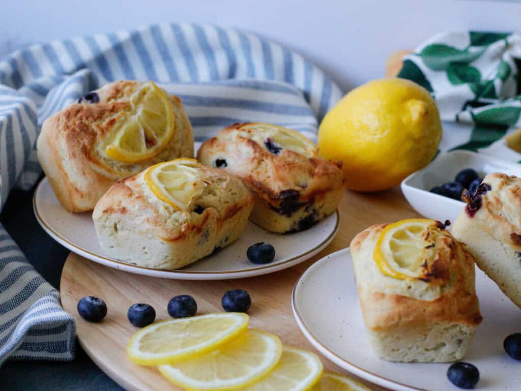 Multiple plates with blueberry lemon mini cakes on them 