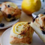 Mini lemon blueberry loaves on a plate with lemons in the background and blueberries scattered on the table