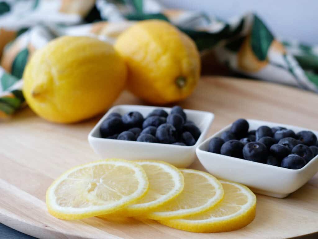Cutting board with bowls of blueberries and sliced lemon
