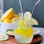 Glass of lemonade with a bowl of cut lemons