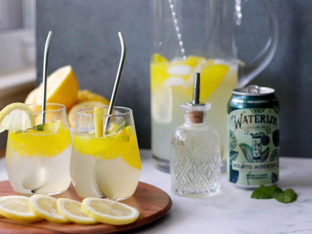 Refreshing lemon mojito cocktails with fresh lemon slices and mint, served in elegant glasses on a wooden tray, perfect for summer drinks.