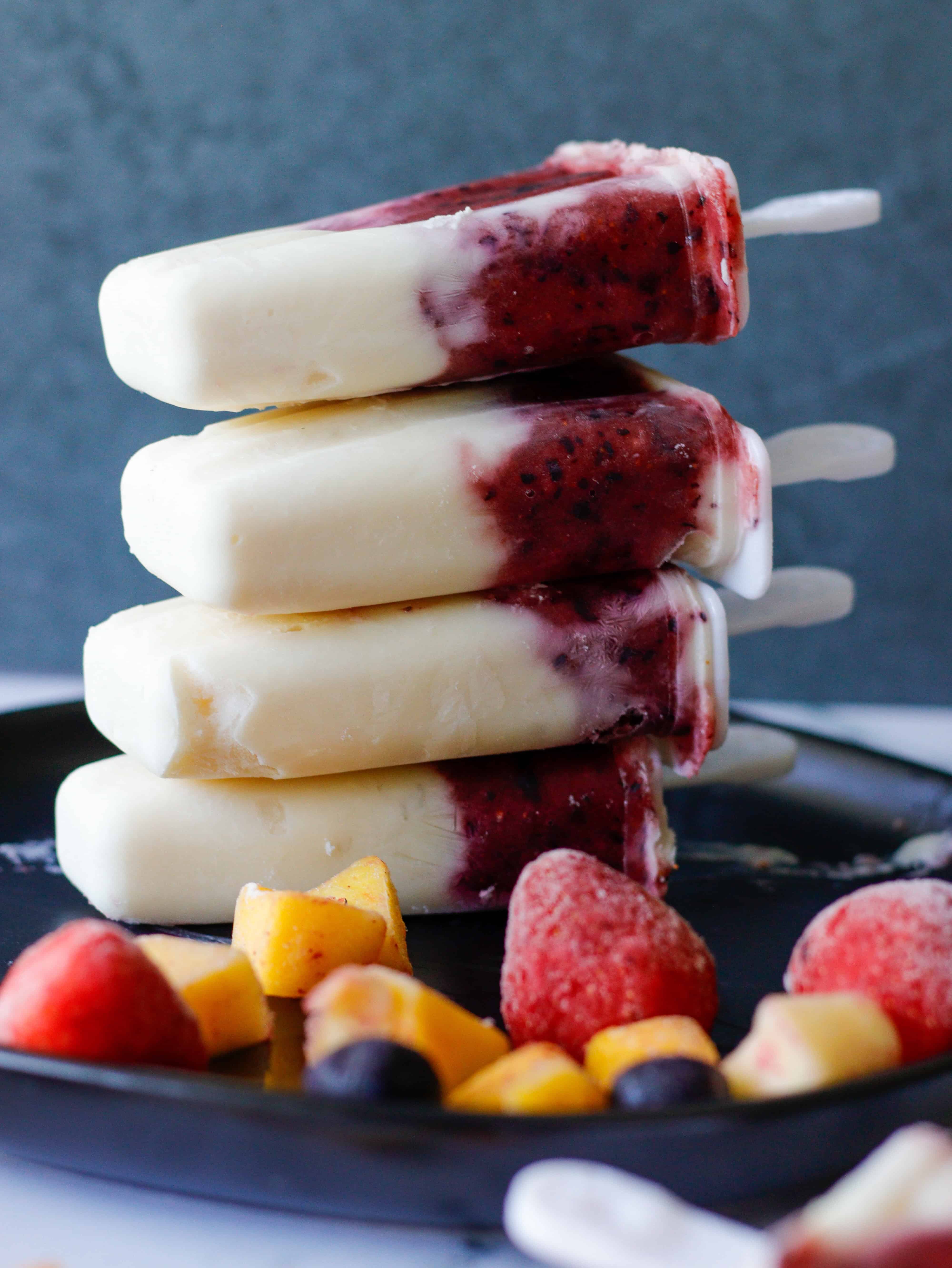 Yogurt and Fruit Bars stacked on a plate with frozen strawberries scattered.