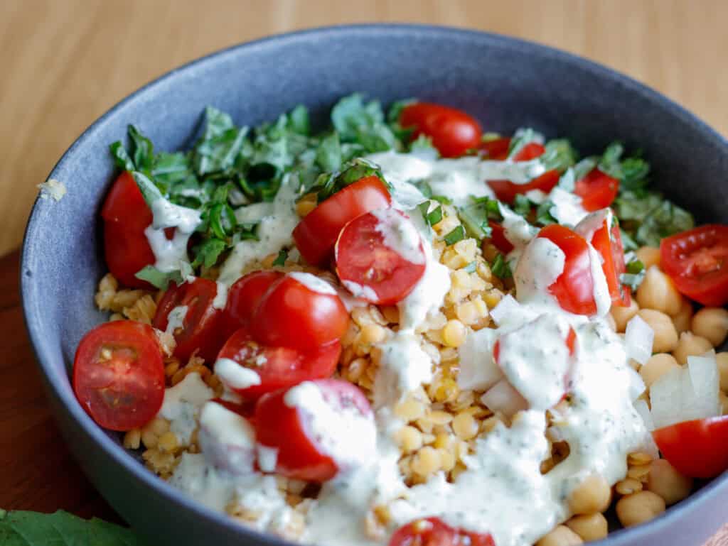 Bowl of lentils, tomato, basil and a creamy dill dressing 