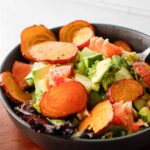 Salad with golden beets, avocado and grapefruit in a gray bowl on a wood counter.