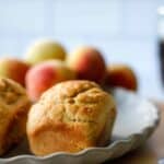 Single mini peach loaf of a gray plate with peaches in the background.
