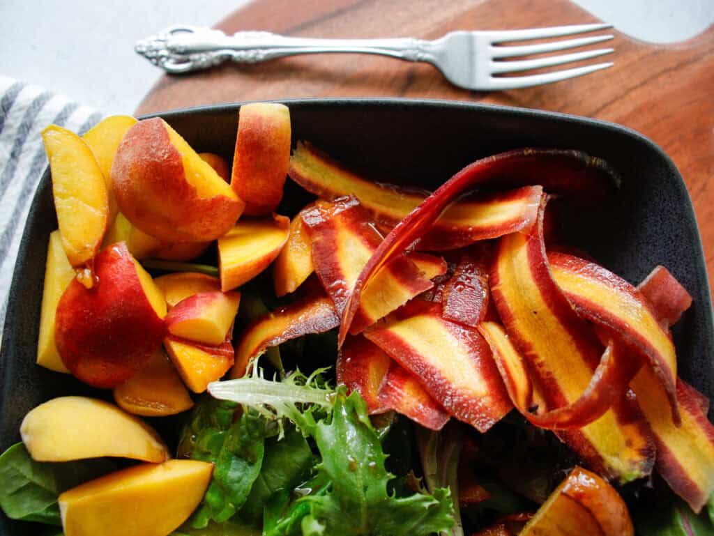 Overhead photo of purples carrots thinly slides into ribbons in a gray bowl