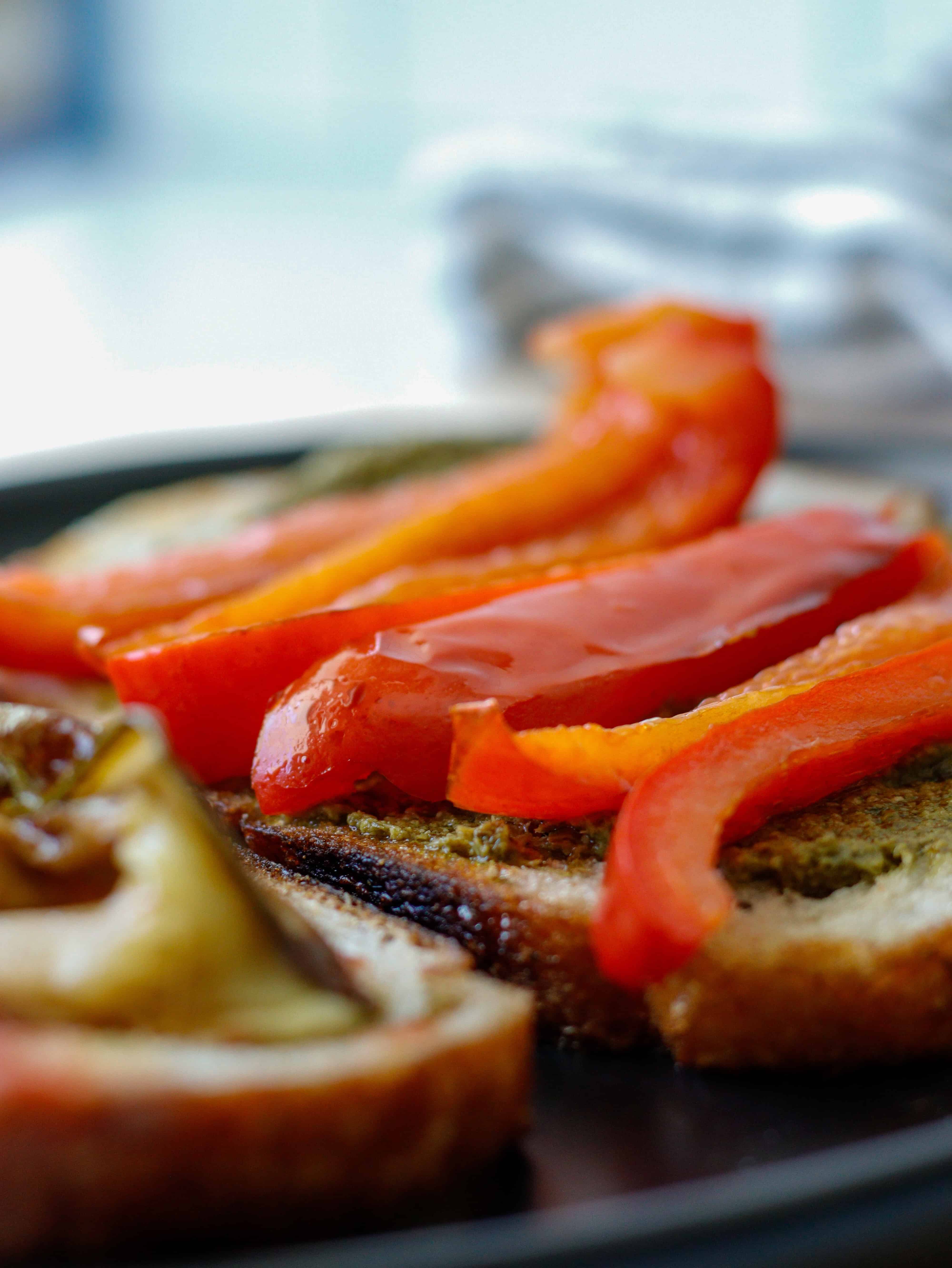 Sliced red peppers on top of bread on a plate