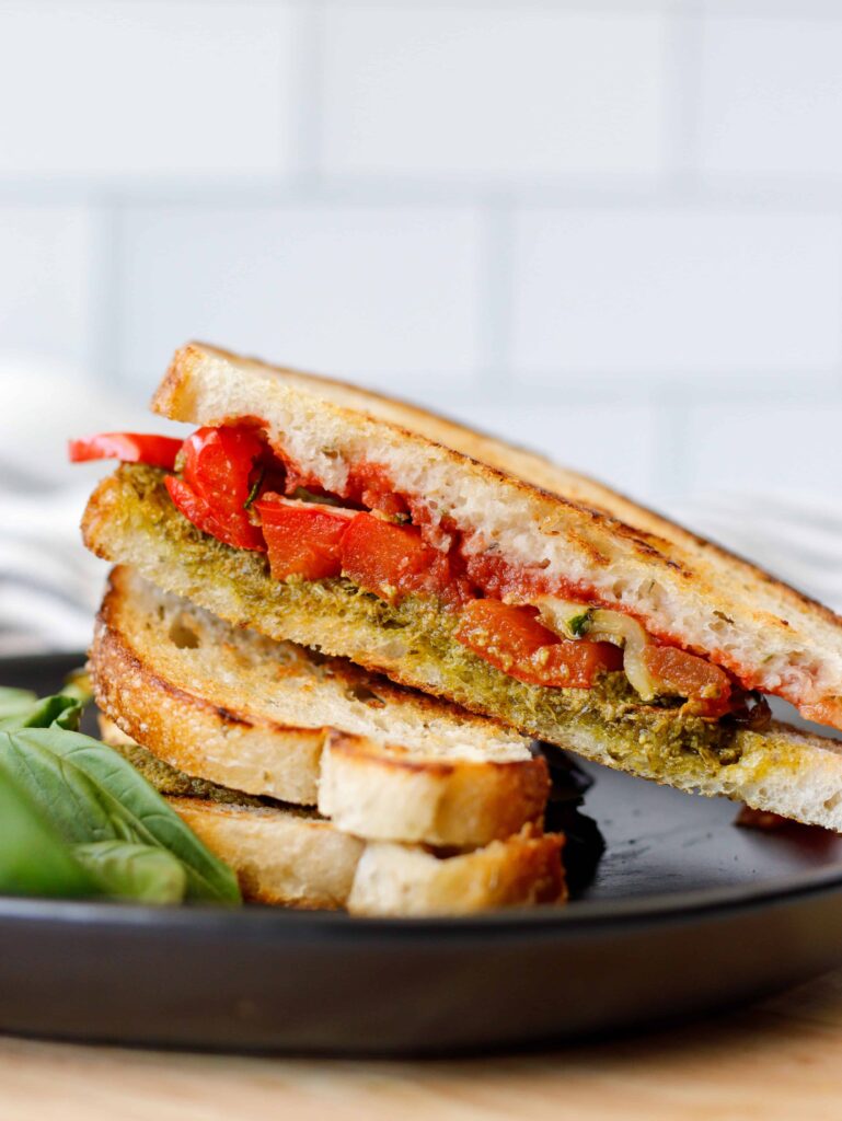 Basil Pesto Sandwich sliced and stacked on a black plate.