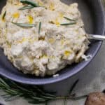Garlic Tahini mashed potatoes in a gray bowl with rosemary garnish.
