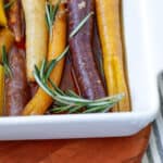 Rainbow carrots in a baking dish with rosemary sprigs on top