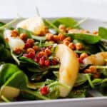 Bed of spinach on a plate close up on pears and pomegranates.