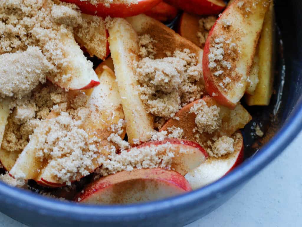Uncooked apples in a saucepan ready to be cooked topped with cinnamon