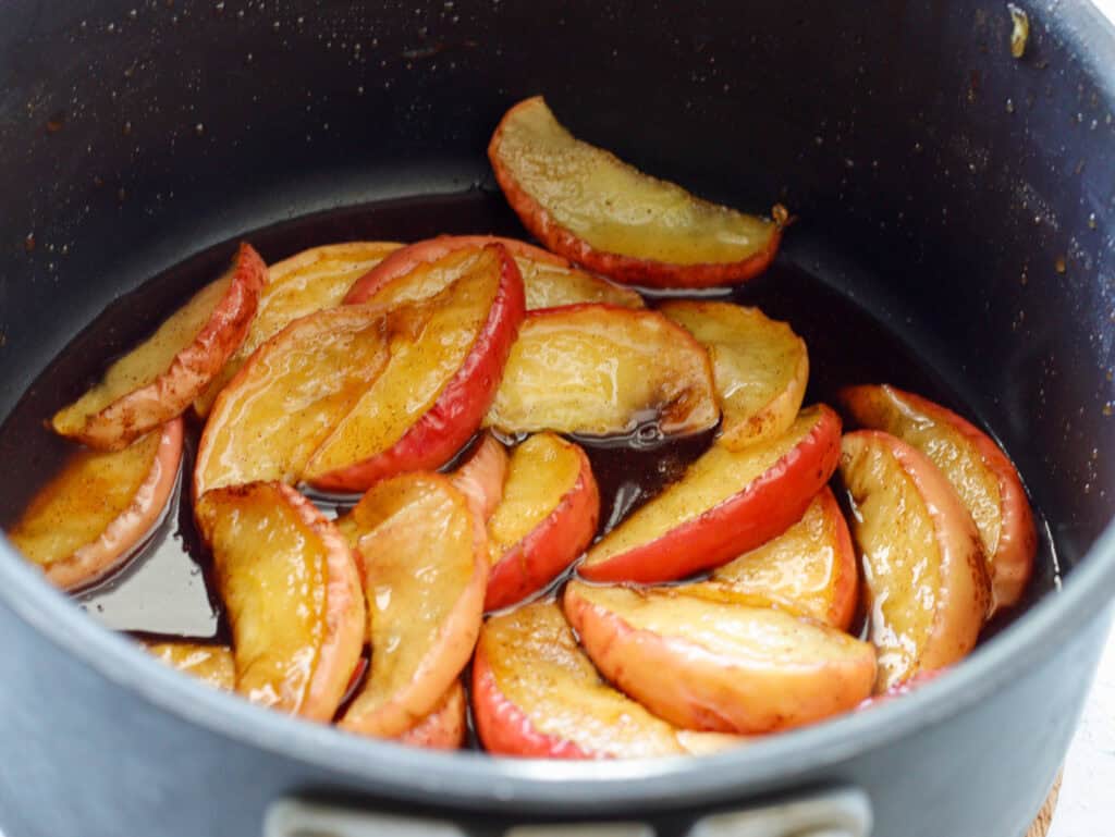 cooked apples in a sauce pan with cinnamon and maple syrup
