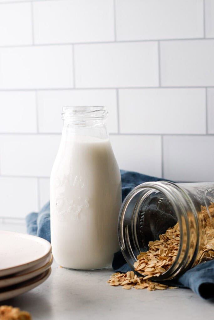 Jug of milk and a mason jar of oats spilled over on a kitchen counter