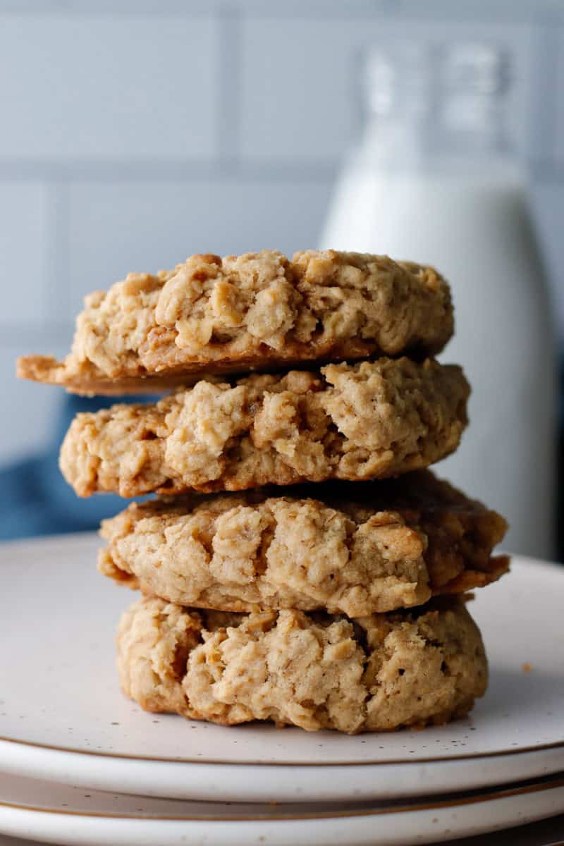 Stack of Oatmeal Chai Cookies on a white plate with a jug of milk behind