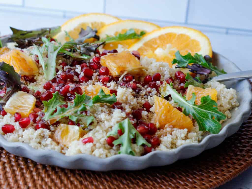 Quinoa salad on a plate with orange slices and pomegranate seeds.