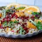 Quinoa salad on a plate with orange slices and pomegranate seeds.