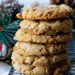 close up stack of large chewy cinnamon almond flour cookies with pine cones in the background