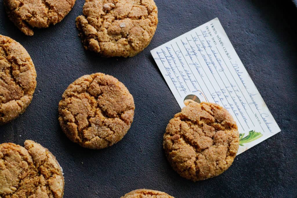 overhead view of chewy cinnamon orange almond flour cookies with a hand written old fashioned recipe card