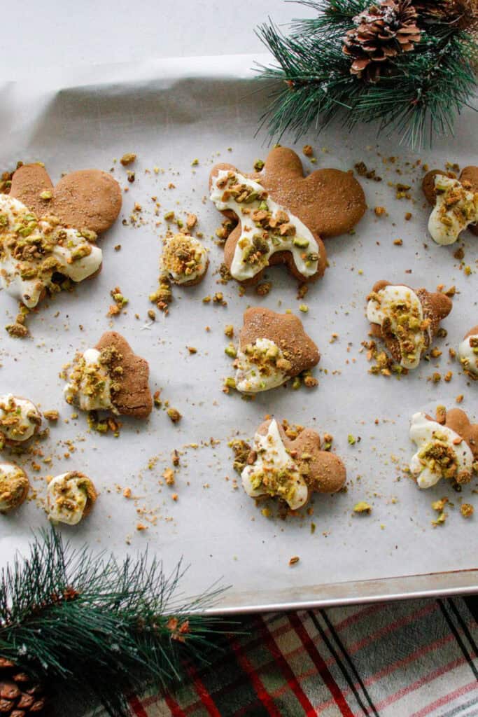 Gingerbread men with white chocolate and pistachio topping on a baking sheet