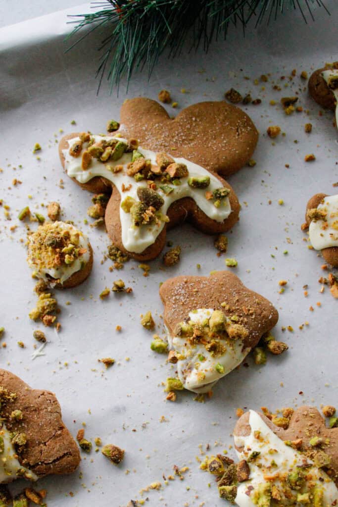Gingerbread men with white chocolate and pistachio topping on a baking sheet