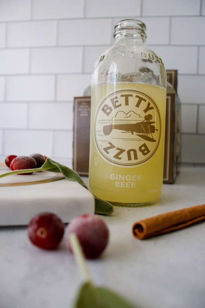 Betty buzz ginger beer with cranberries and cinnamon sticks in the foreground