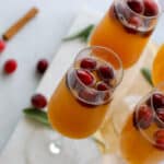 Overhead view of 4 champagne flutes filled with ginger apple fizz mocktail and cranberries