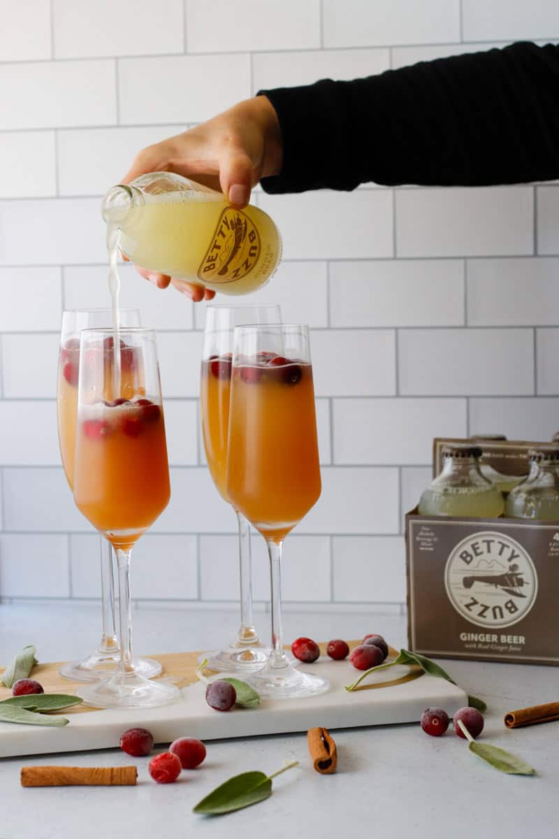 Hand pouring ginger beer into champagne flutes